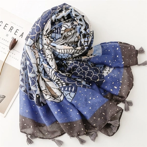 Detail of blue-grey printed scarf with gold foil dots and elegant grey tassels