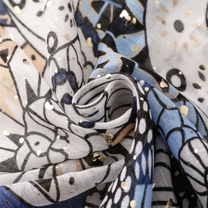 Detail of white scarf with gold foil dots and blue geometric patterns on light fabric