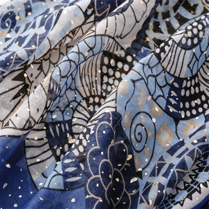 Detail of blue printed scarf with gold foil accents and lightweight pleated fabric texture