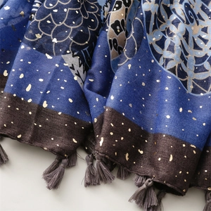 Detail of blue and brown scarf featuring golden mandala foil print and grey cotton tassels