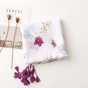 Detail of white cotton linen scarf with purple floral print and elegant fringe tassels