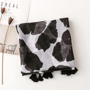 Detail of black and white ginkgo leaf print scarf with elegant fringe tassels