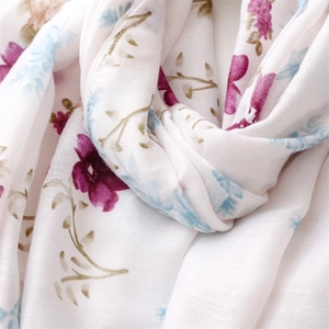 Close-up of lightweight white cotton scarf with delicate purple floral print and soft texture