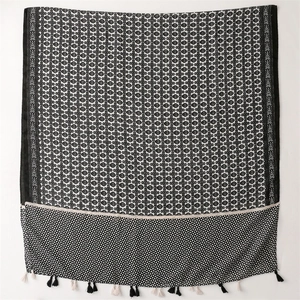 Detail of black and white geometric pattern and fringe tassels on a soft linen shawl