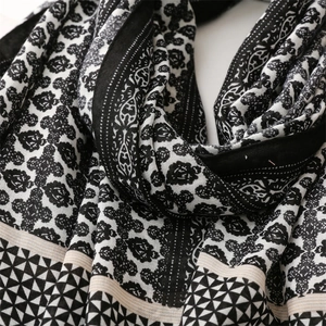 Close-up of linen-feel scarf showing floral geometric patterns and fringe detail