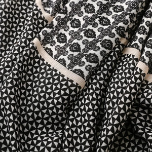 Macro detail of geometric patterns and floral motifs on soft cotton-linen scarf fabric