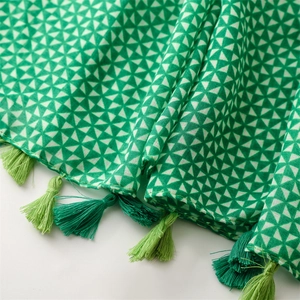Detailed close-up of geometric pattern and emerald green tassels on cotton-linen scarf