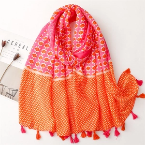 Pink and orange cotton-linen scarf with floral patterns and soft tassels on white desk