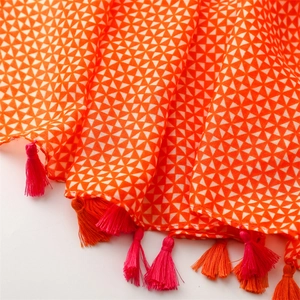 Detailed close-up of orange geometric patterns and colorful tassels on a linen scarf