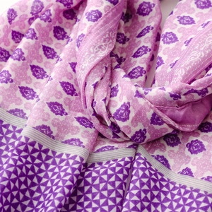 Detail of purple floral scarf featuring geometric patterns and soft tassel fringe