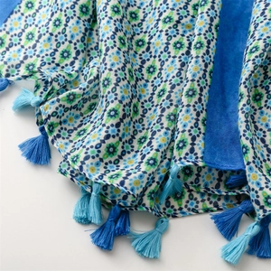 Detail of floral linen-feel shawl featuring blue fringe tassels and intricate patterns