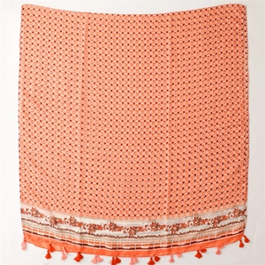 Detail eines warmen orangen Schals mit geometrischem Muster und weichen Quasten