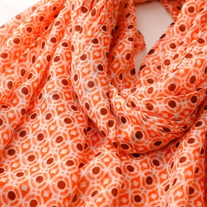 Detailaufnahme des orangefarbenen Schals mit geometrischem Muster und weichem Faltenwurf