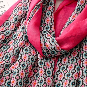Close-up detail of soft rose pink cotton scarf with bohemian floral print and tassels