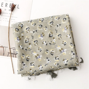 Detail of sage green floral scarf featuring delicate yellow prints and fringe edges