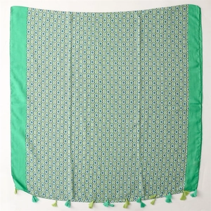 Close-up of geometric floral pattern on linen scarf with vibrant green tassels
