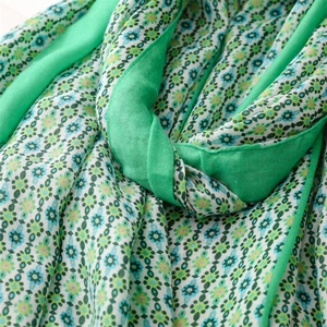 Detailed macro shot of green floral pattern texture and solid green hem on a soft scarf