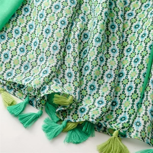 Detail of bohemian emerald green scarf featuring geometric prints and dual-color tassels