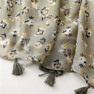 Close-up of lightweight floral scarf with refined fringe tassels and soft green texture