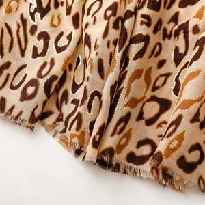Macro detail of leopard print scarf featuring gold foil accents and soft frayed edges