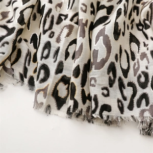 Detailed macro view of leopard print scarf fabric with metallic threads and frayed edges