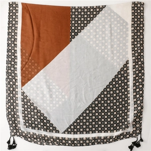 Detail of color-block geometric scarf with black tassels and polka dot print fabric