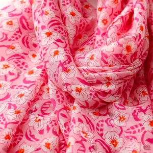 Detail shot of pink floral print scarf fabric showing soft texture and tassel detail