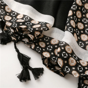 Detail of printed scarf featuring geometric patterns, bold color blocks, and black fringe