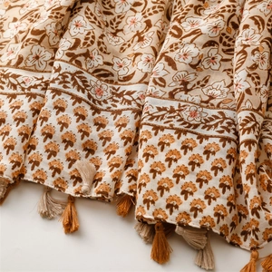 Macro detail of bohemian floral linen scarf with intricate fringe and warm earthy tones