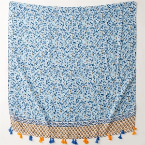 Close-up of blue floral cotton linen scarf featuring orange and blue fringe tassels