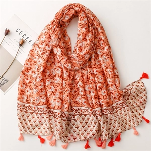 Detail of orange bohemian floral scarf with soft tassels and premium linen texture