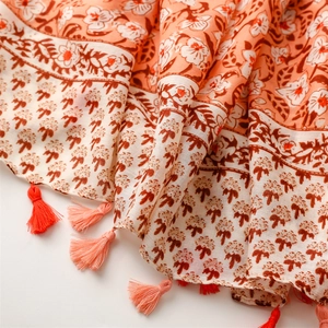 Close-up of floral print scarf in coral orange with delicate bohemian tassels
