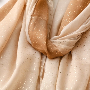 Close-up of lightweight gradient scarf featuring golden glitter and frayed edges