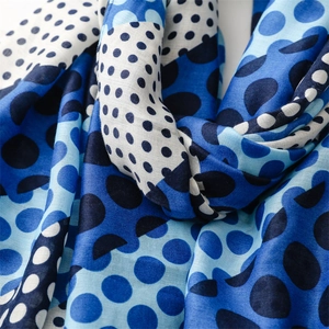 Macro detail of blue polka dot scarf showing soft cotton-linen texture and fringed edges