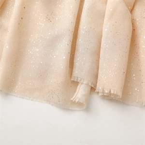 Detail of light champagne linen-feel scarf with gold foil dots and frayed edges