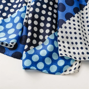 Close-up of blue and white polka dot scarf fabric with light texture and hemmed edge