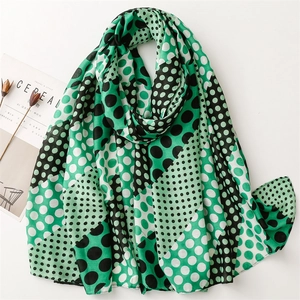 Detail of green polka dot scarf showing lightweight fabric texture and soft frayed edges