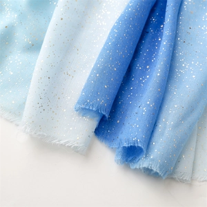Detailed macro of blue gradient linen scarf with gold foil accents and frayed edges
