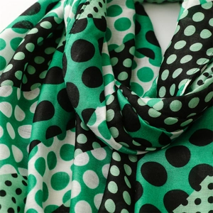 Detail view of soft cotton-linen scarf fabric with vibrant green polka dot pattern