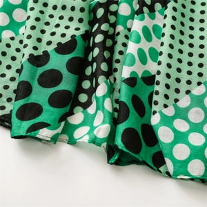 Detailed macro view of soft cotton-linen scarf featuring green and black polka dot patterns