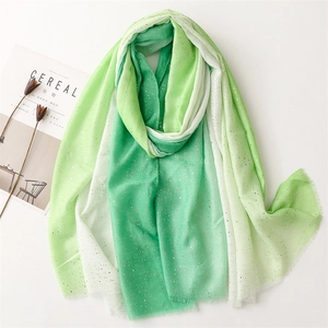 Close-up of lightweight gradient green linen-feel scarf with gold foil accents and raw edges