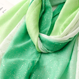 Close-up of green gradient linen scarf with fine gold glitter and frayed edges