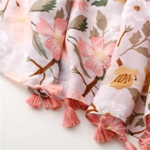 Close-up of pink floral scarf with delicate fringe edges and soft summer fabric texture