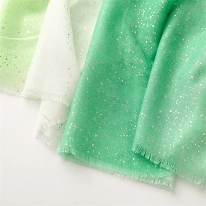 Detail of green gradient scarves with shimmering gold glitter and raw fringe edges