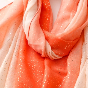 Detail of gradient orange scarf with golden glitter dots on textured soft fabric