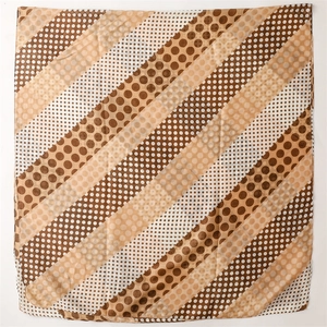 Detailed view of square scarf with polka dot pattern in coffee and beige tones