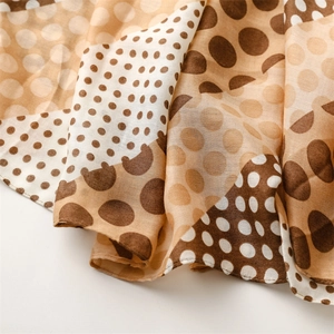 Detail of soft cotton-linen scarf featuring brown polka dot patterns and fine rolled edges