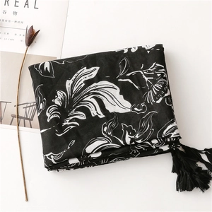 Close-up of black floral scarf with fringe details and elegant botanical patterns