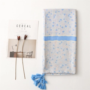 Close-up of lightweight floral scarf with blue tassels and elegant flower pattern