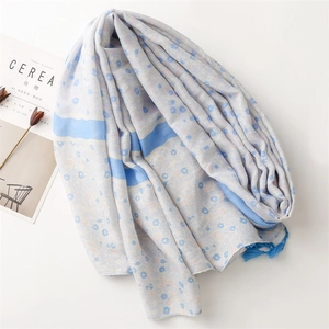 Detail showing blue floral pattern scarf with soft fringe edges and linen texture